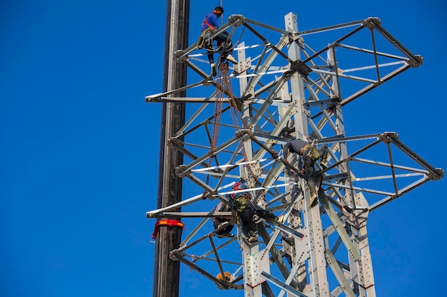 Lavoratori di sesso maschile installazione di pali elettrici di trasmissione ad alta tensione colonna in linea lavori in acciaio a rischio di altezza