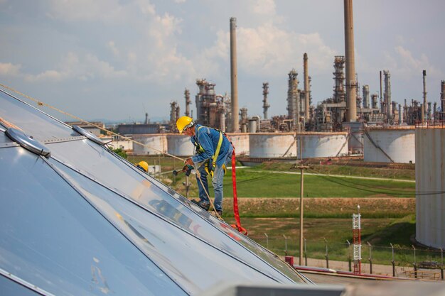 Male workers rope access height safety connecting with a knot safety harness clipping into roof construction site oil tank dome