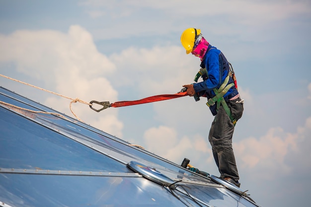 Male workers rope access height safety connecting with a knot safety harness, clipping into roof fall arrest and fall restraint anchor point systems ready to ascending, construction site oil tank dome