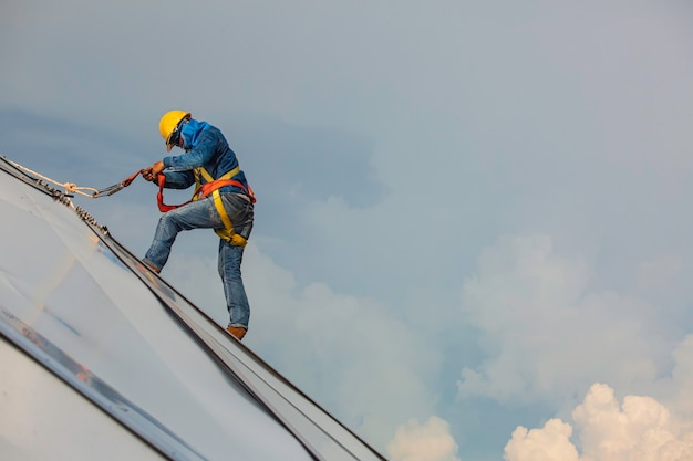 Male workers rope access height safety connecting with a knot\
safety harness, clipping into roof fall arrest and fall restraint\
anchor point systems ready to ascending, construction site oil tank\
dome