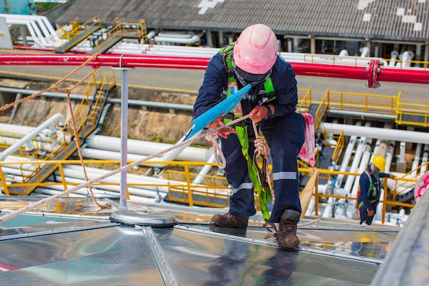 Male workers rope access height safety connecting with a knot
safety harness clipping into roof fall arrest and fall restraint
anchor point systems ready to ascending construction site oil tank
dome