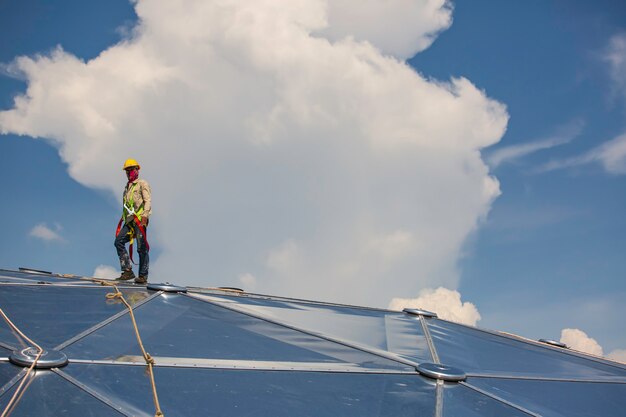 Male workers rope access height safety connecting with a knot\
safety harness, clipping into roof fall arrest and fall restraint\
anchor point systems ready to ascending, construction site oil tank\
dome