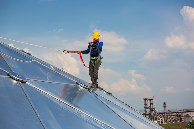 Male workers rope access height safety connecting with a knot\
safety harness, clipping into roof fall arrest and fall restraint\
anchor point systems ready to ascending, construction site oil tank\
dome