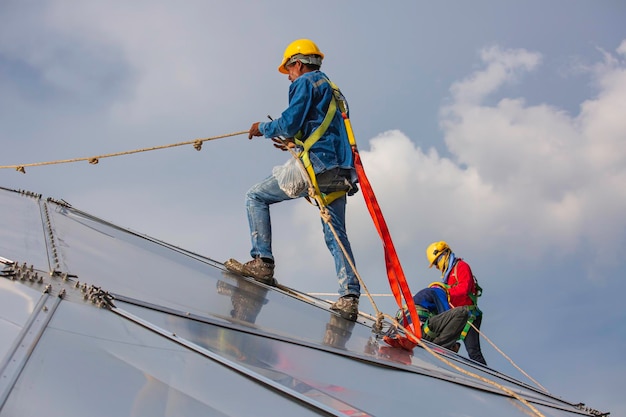 Male workers rope access height safety connecting with a knot
safety harness, roof fall arrest and fall restraint anchor point
systems ready to ascending, construction site oil tank dome