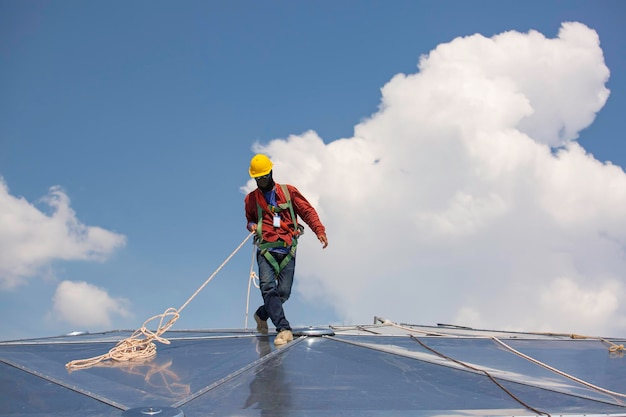 Male workers rope access height safety connecting with a knot\
safety harness, roof fall arrest and fall restraint anchor point\
systems ready to ascending, construction site oil tank dome