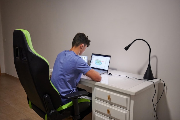 A male working on the laptop with a lamp and a desk with text\
study hard time