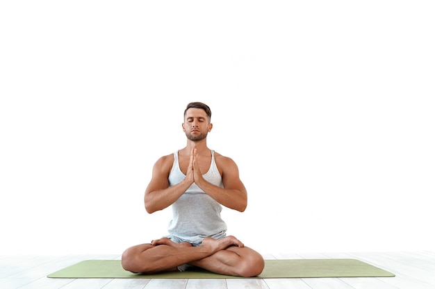 Male yoga maditates in classical pose in studio on white 