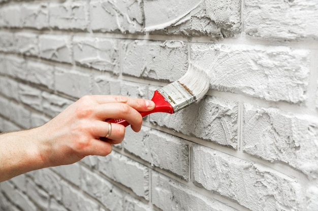 브러시 흰색 벽돌 벽으로 그린 남성 손 리노베이션 작업 흰색 배경