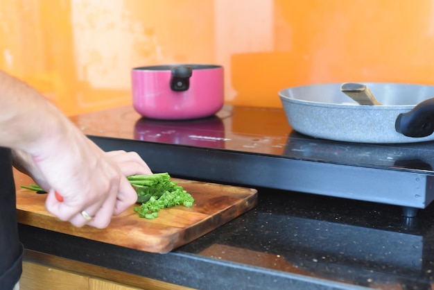 males hands cutting green onion on wooden board for cooking japanese ramen