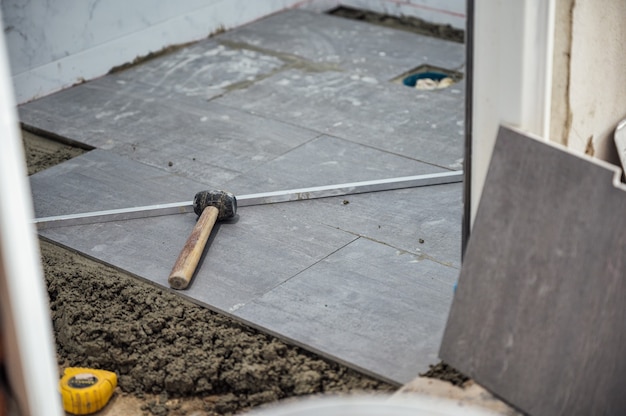 Mallet and tools on granite tile during laying floor