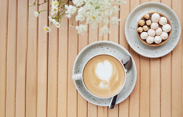 Malse hazelnoottaart en cappuccino in witte keramische beker op houten tafel op het terras bij koud herfstweer Esthetisch ontbijt Kopieerruimte