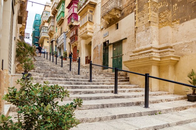 Malta Valletta 2019년 6월 16일: 발렌시아 구시가지의 밝고 화려한 건물 사이에 계단이 있는 빈 거리