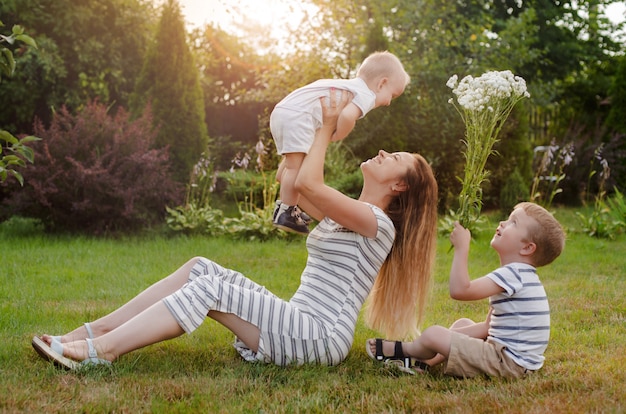 Mam, twee kinderen rusten op de natuur. Rivaliteit tussen broers en zussen. Broeders, moederschap.