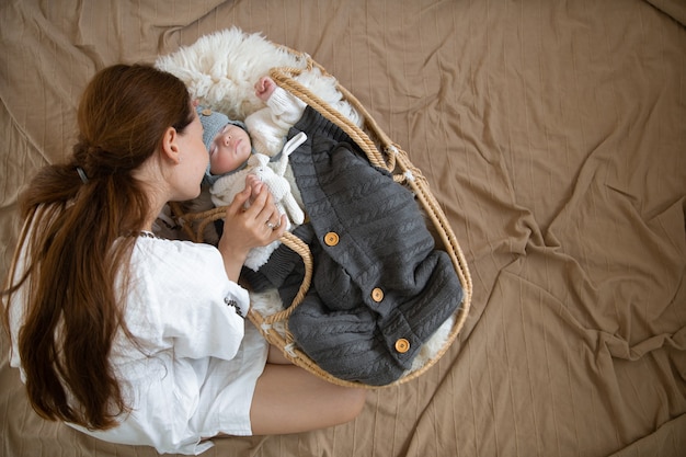 Mama en baby, die heerlijk slapen in een rieten wieg in een warme gebreide muts onder een warme deken.