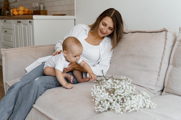 mama en baby op bed met een boeket witte bloemen