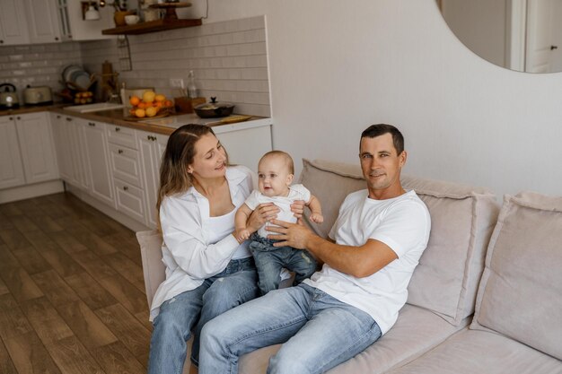 mama en papa spelen op de bank met hun zoon bij de grote ramen