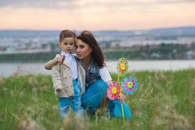 Mama knuffelt baby en wervelt met hem zomerwandeling op het veld bewolkte dag telefoto-opname