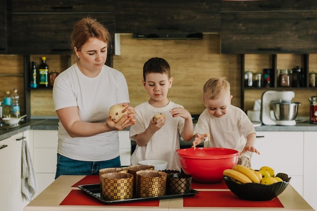 mama met kinderen kneedt het deeg voor heerlijke gebakjes die ze thuis in de keuken bereiden