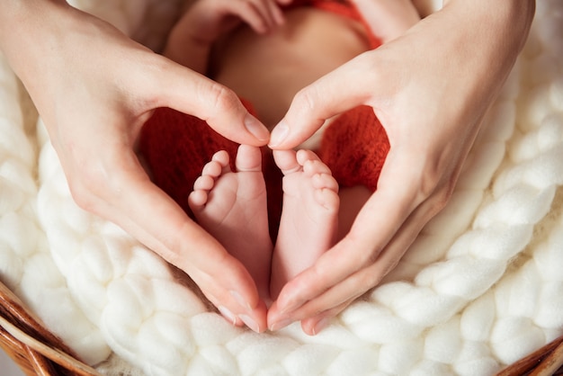 Мамины руки в форме сердца держат ноги новорожденного