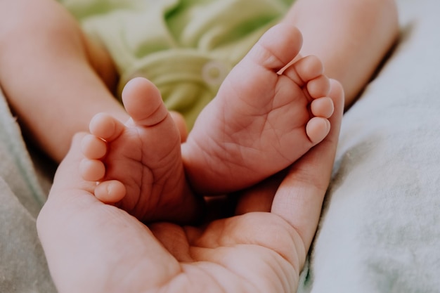 Mama's hand houdt schattige kleine pasgeboren babyvoetjes vast