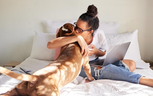 Mama says chocolates bad but I can have her kisses Shot of a beautiful young woman using a laptop while relaxing with her dog in bed at home