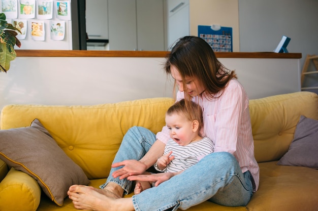 Mama speelt thuis met een klein kind op de bank veel plezier