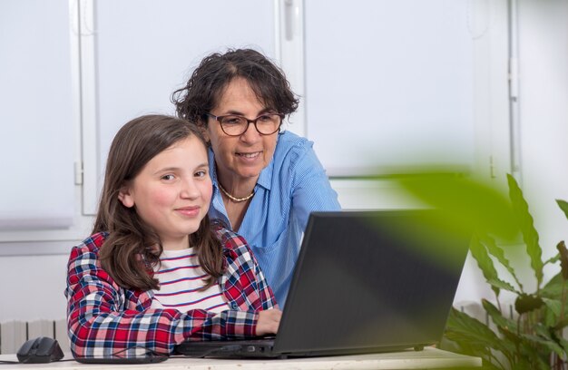 Mamma en dochter die laptop thuis met behulp van