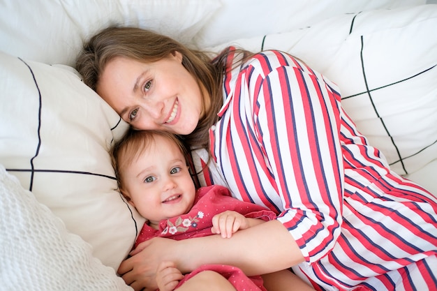 Foto mamma met haar dochter die en op het bed ligt ligt