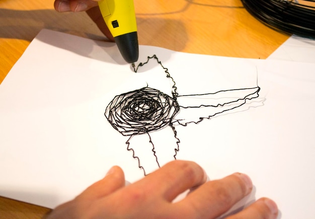 Man 3d pen draws a flower on white paper