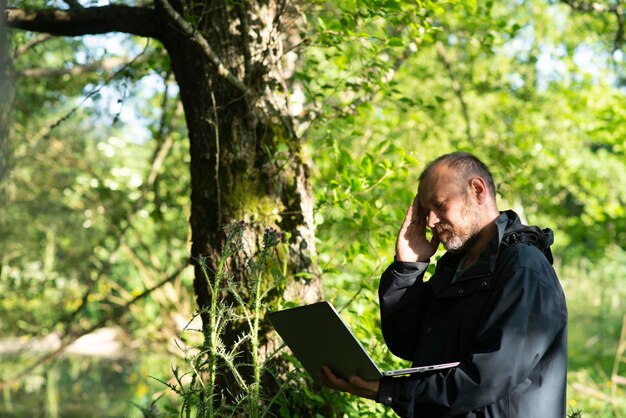 Man 43 jaar oud in het bos met een laptop