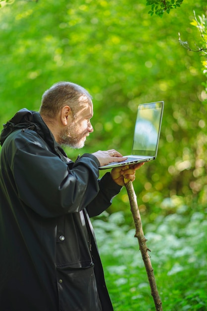 Man 43 jaar oud in het bos met een laptop