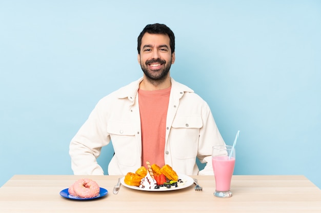 Man aan een tafel met ontbijtwafels en een milkshake