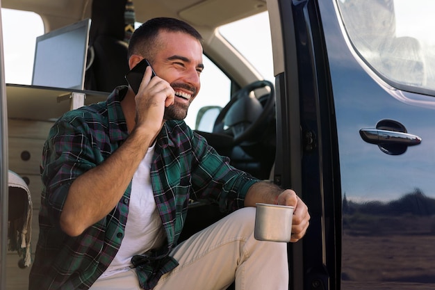 Man aan het telefoneren in de deur van zijn busje