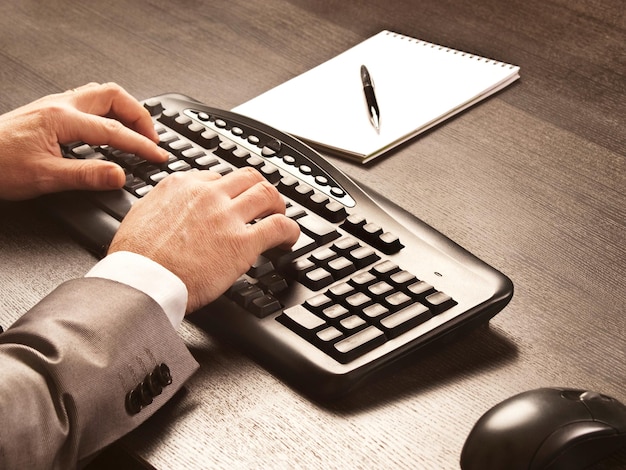 Man aan het werk aan een bureau met een computertrefwoord