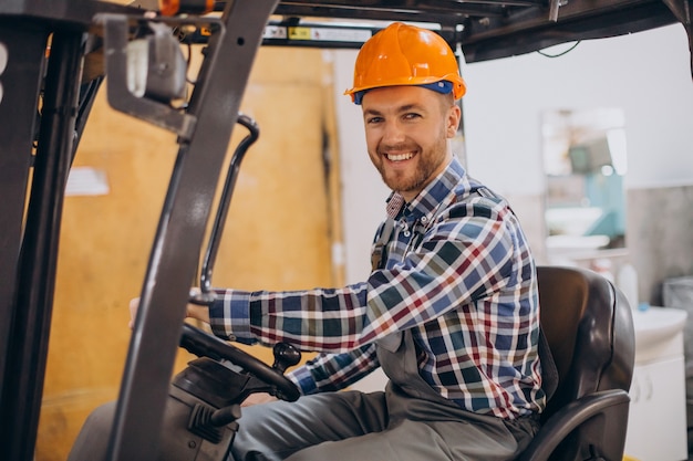 Man aan het werk in het magazijn en heftruck rijden