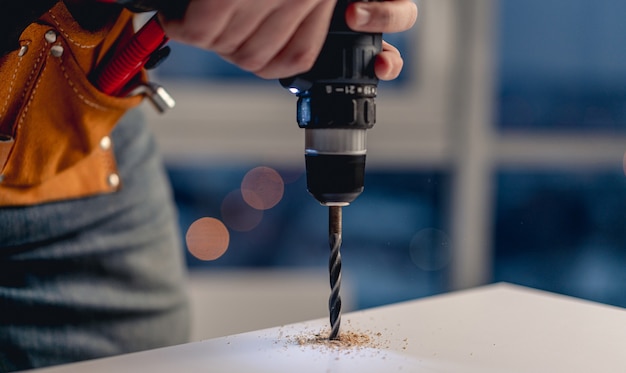 Foto man aan het werk met elektrische schroevendraaier en schroeven tijdens het proces van meubelproductie