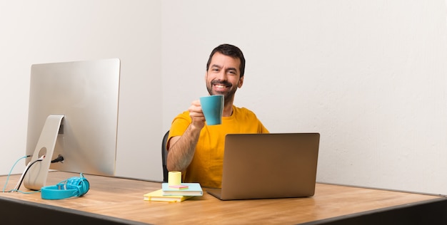 Man aan het werk met laptot in een kantoor met een kopje koffie