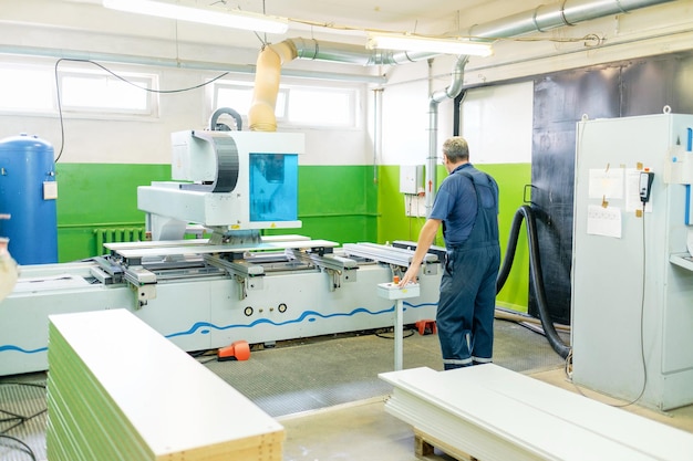 Man aan het werk op cnc-machines in de meubelfabriek Houten meubelproductie Schrijnwerkerij