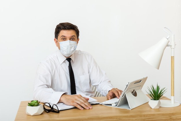 Man aan het werk op kantoor in een medisch masker