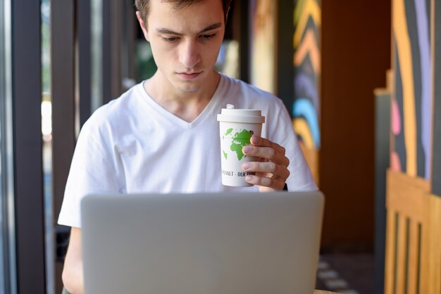 Man aan het werk op laptop en drinken uit een herbruikbare kop koffie