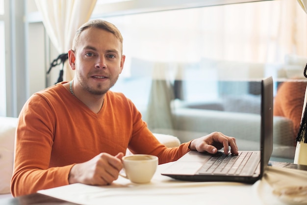 Man aan het werk op notebook kijken naar camera in café