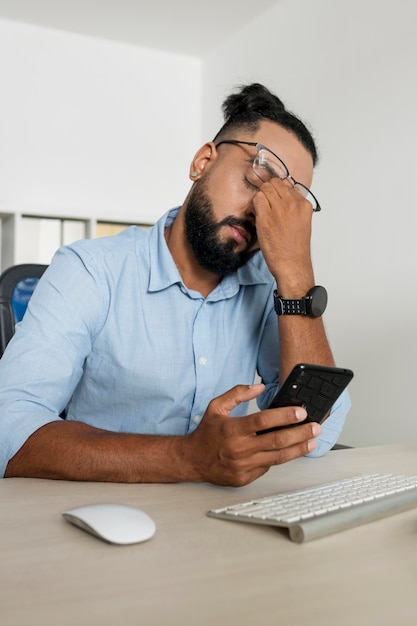 Man aan het werk terwijl hij zijn telefoon checkt