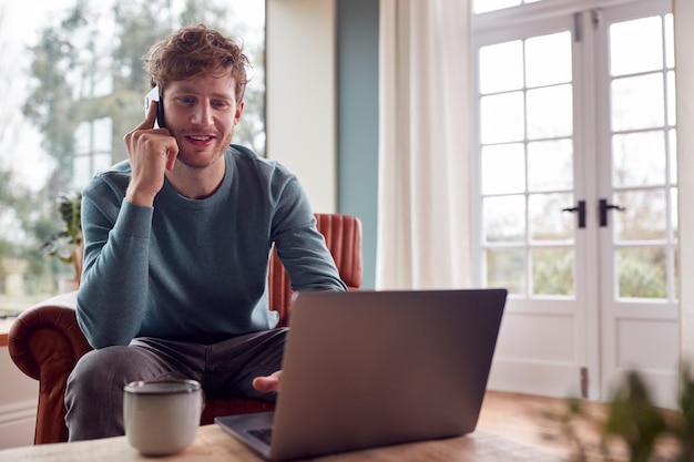 Foto man aan het werk vanuit huis met behulp van laptop en mobiele telefoon