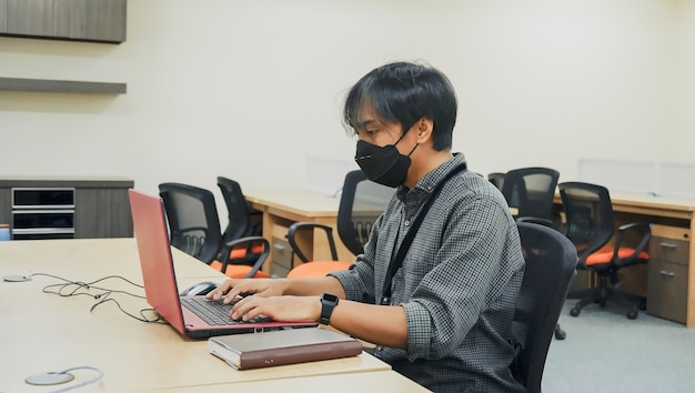 man aan het werk voor een laptop die een masker draagt