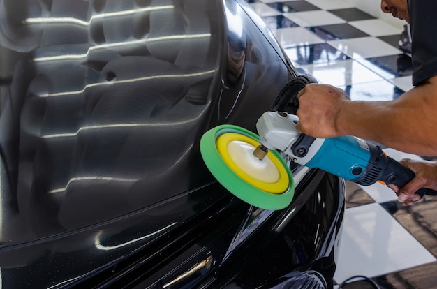 Man aan het werk voor het polijsten, coaten van auto's. polijsten van de auto helpt bij het verwijderen van verontreinigingen op het oppervlak van de auto.
