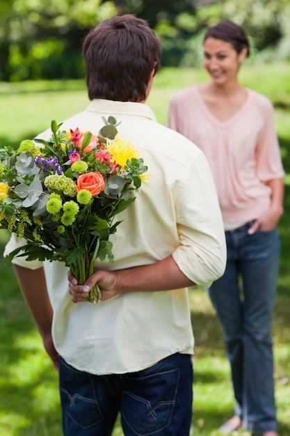 L'uomo sta per sorprendere il suo amico con un mazzo di fiori