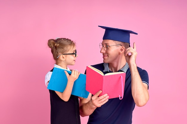 Man in academic hat holding book, study together with cute preteen girl in school uniform