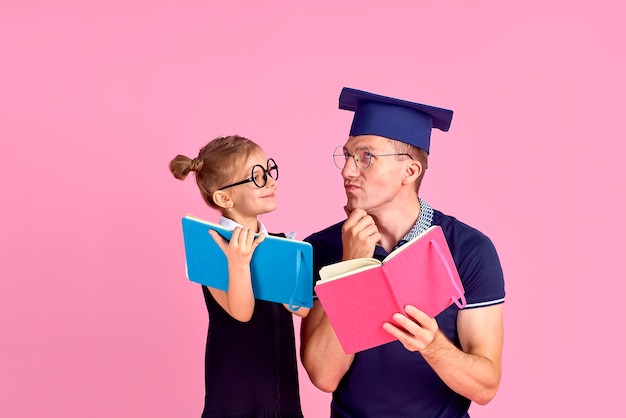 Man in academic hat holding book, study together with cute preteen girl in school uniform