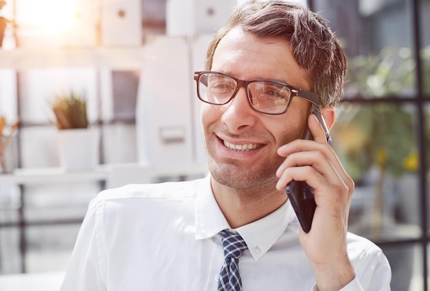 Foto man accountant of bedrijfsadvocaat die op zijn smartphone praat met financieel papierwerk op zijn werkplaats