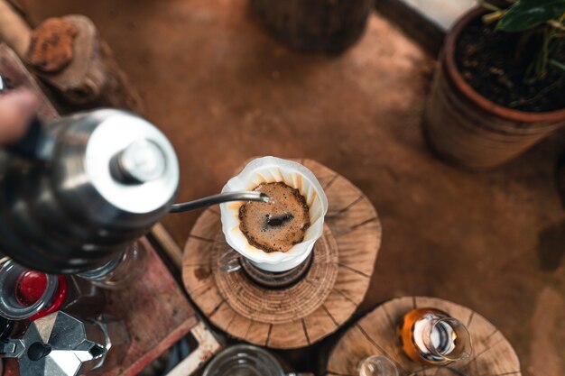 Man adding hot water into coffee dripper above glass jar.